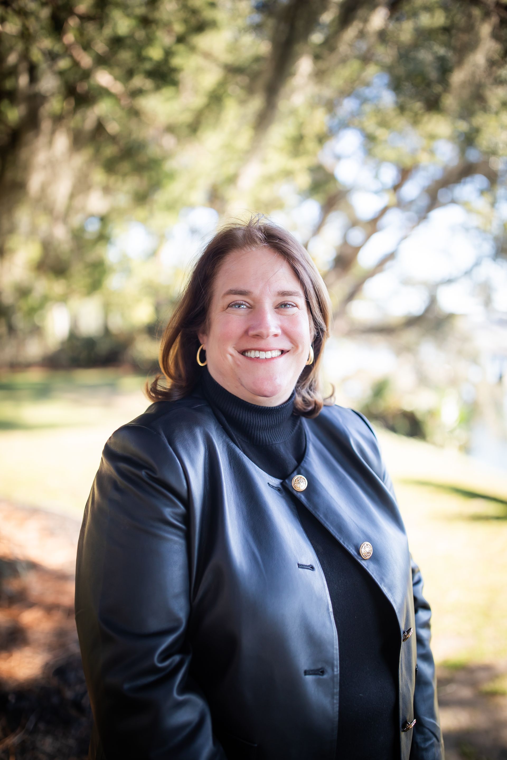 A woman in a black jacket is smiling for the camera.
