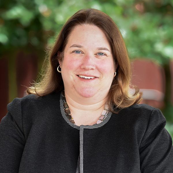 A woman in a black jacket is smiling for the camera.