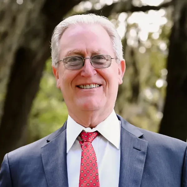 A man in a suit and tie is smiling for the camera