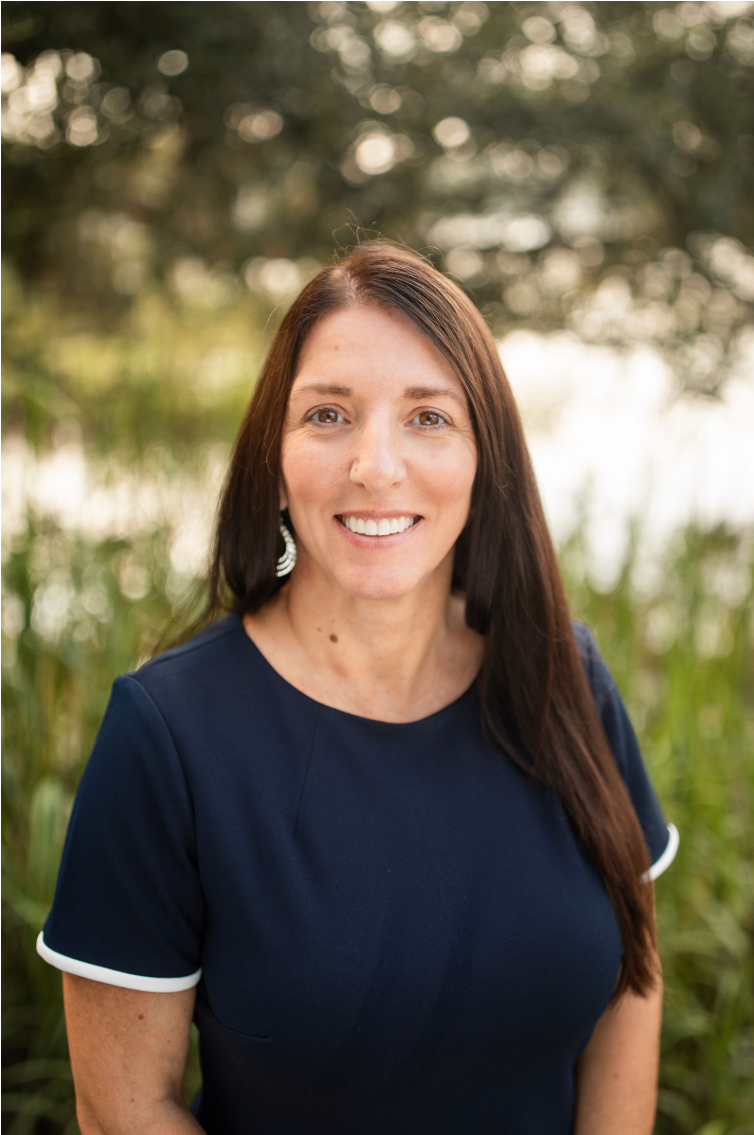 A woman wearing a red and black plaid jacket is smiling for the camera.