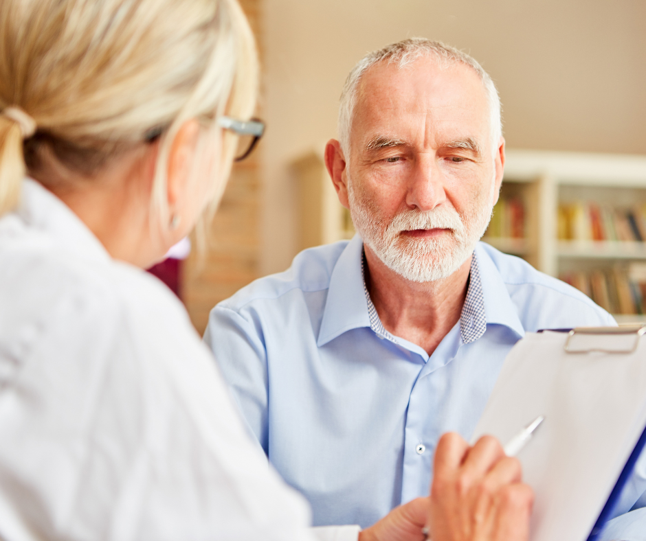 A man with a beard is talking to a woman while holding a clipboard.