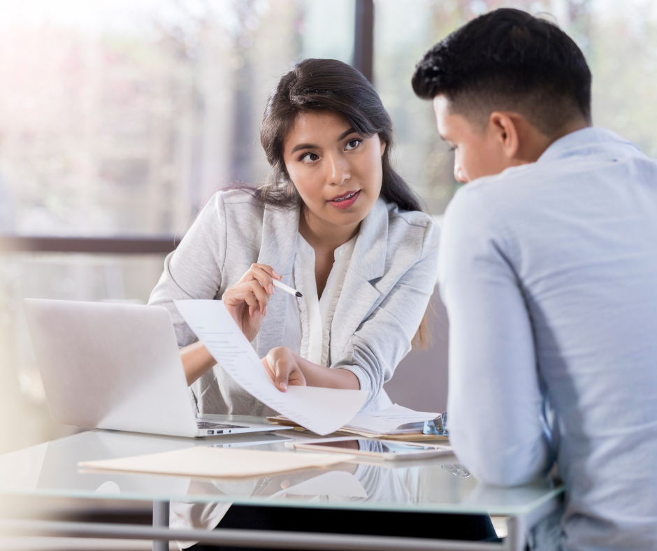 A man and a woman are sitting at a table looking at a piece of paper.