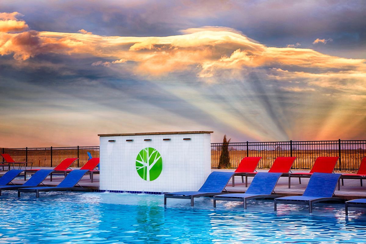 Poolside scene with lounge chairs, bar, and dramatic sunset.