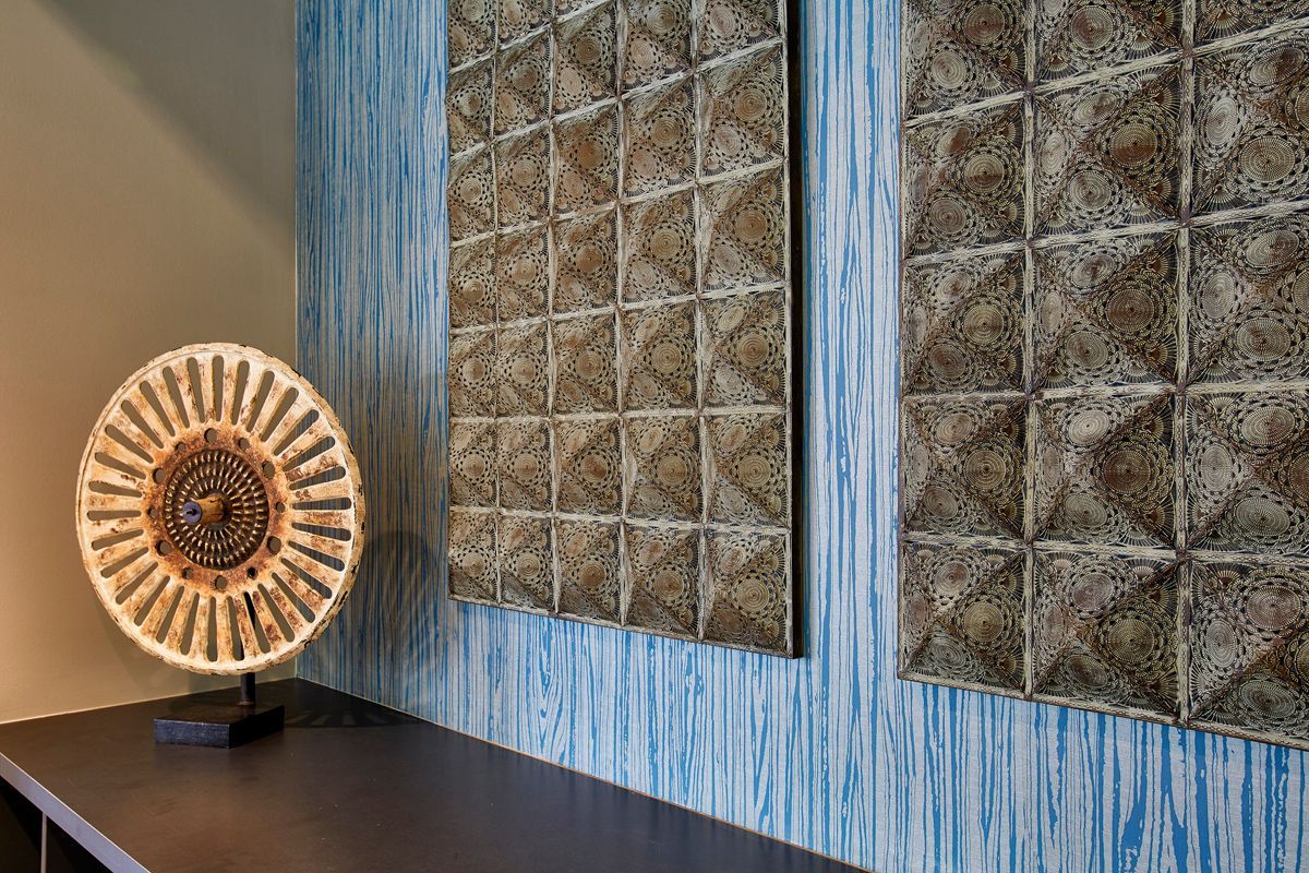 Decorative wall panels and art on a table against a blue textured wall.
