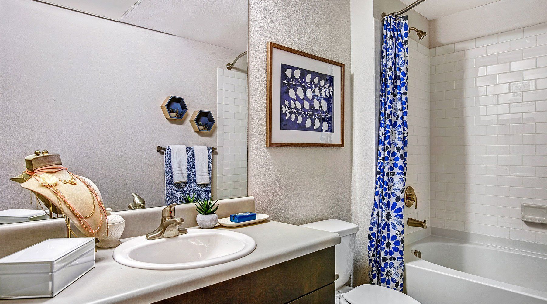 Bathroom with a sink, mirror, and a bathtub with a blue and white patterned shower curtain.