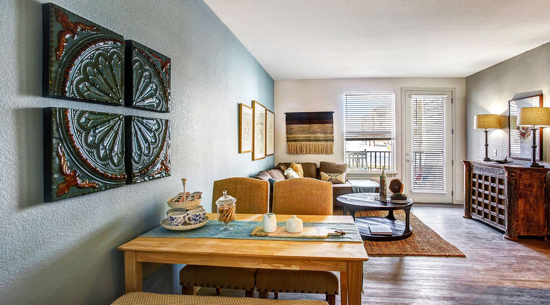 Living room with wooden furniture, art on blue wall, and view of a balcony.