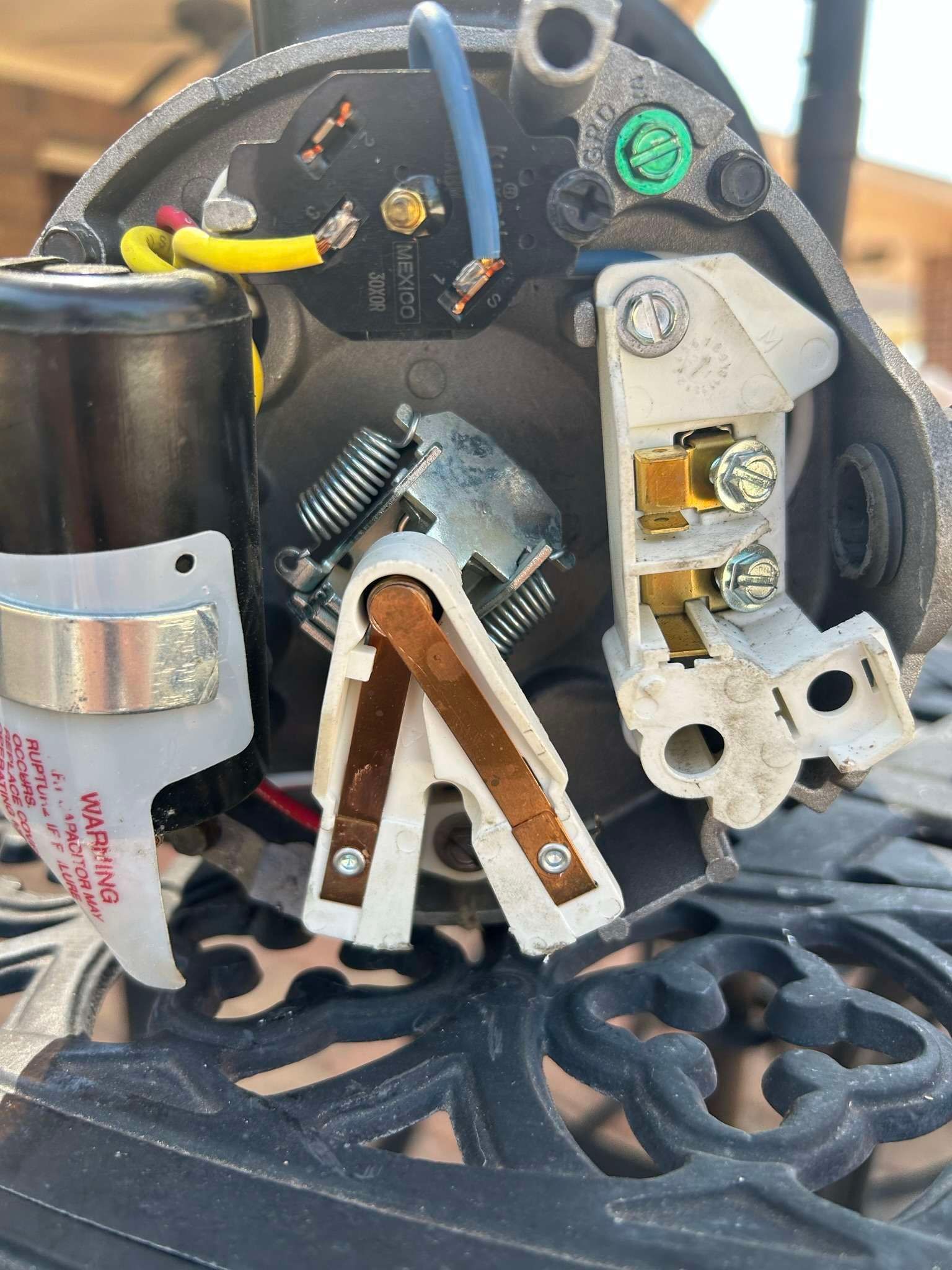 Close-up of electrical components; wiring, terminal blocks, spring, and motor brushes within a black housing.