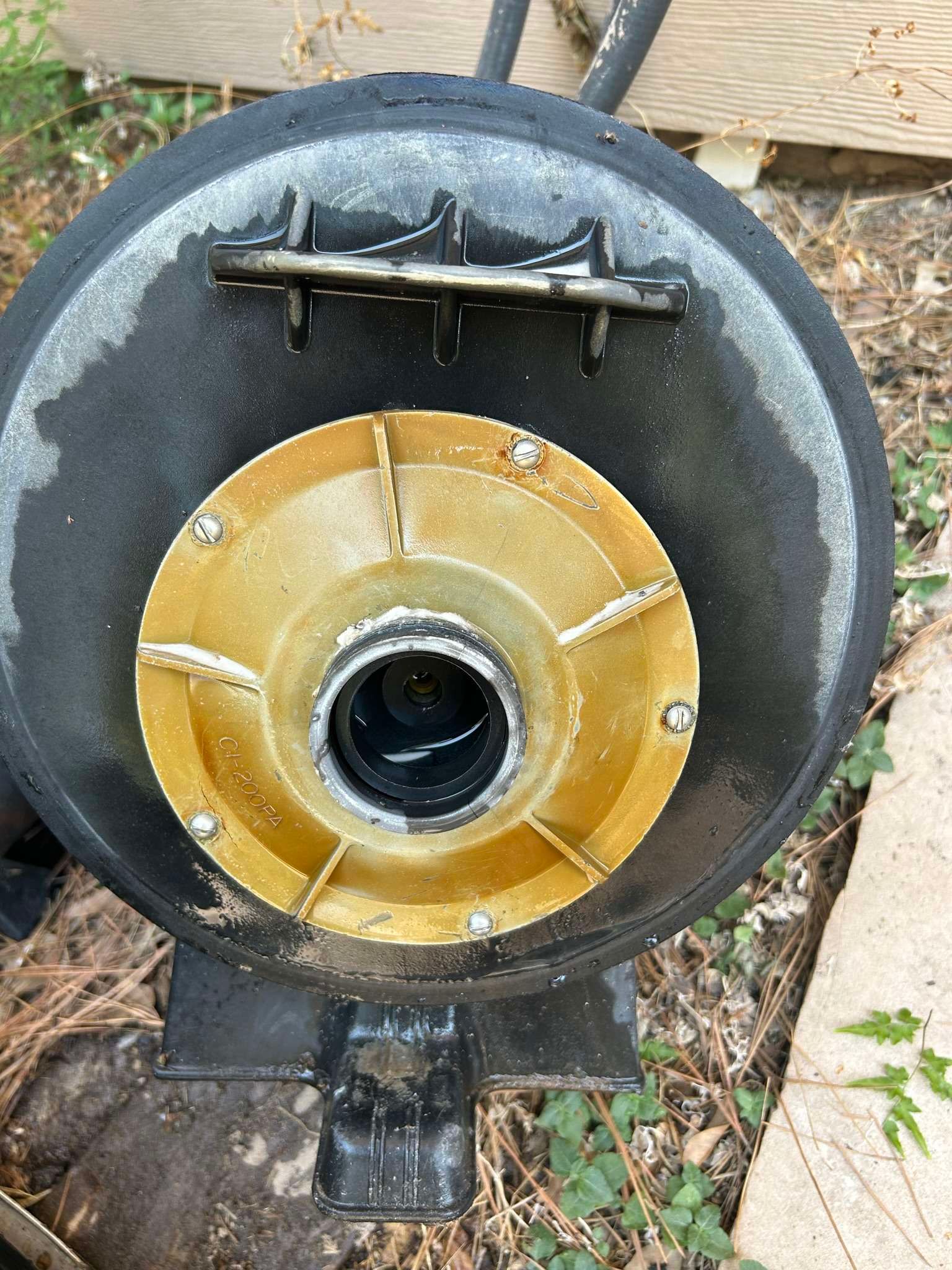 Black and yellow swimming pool filter with visible interior, located outdoors.