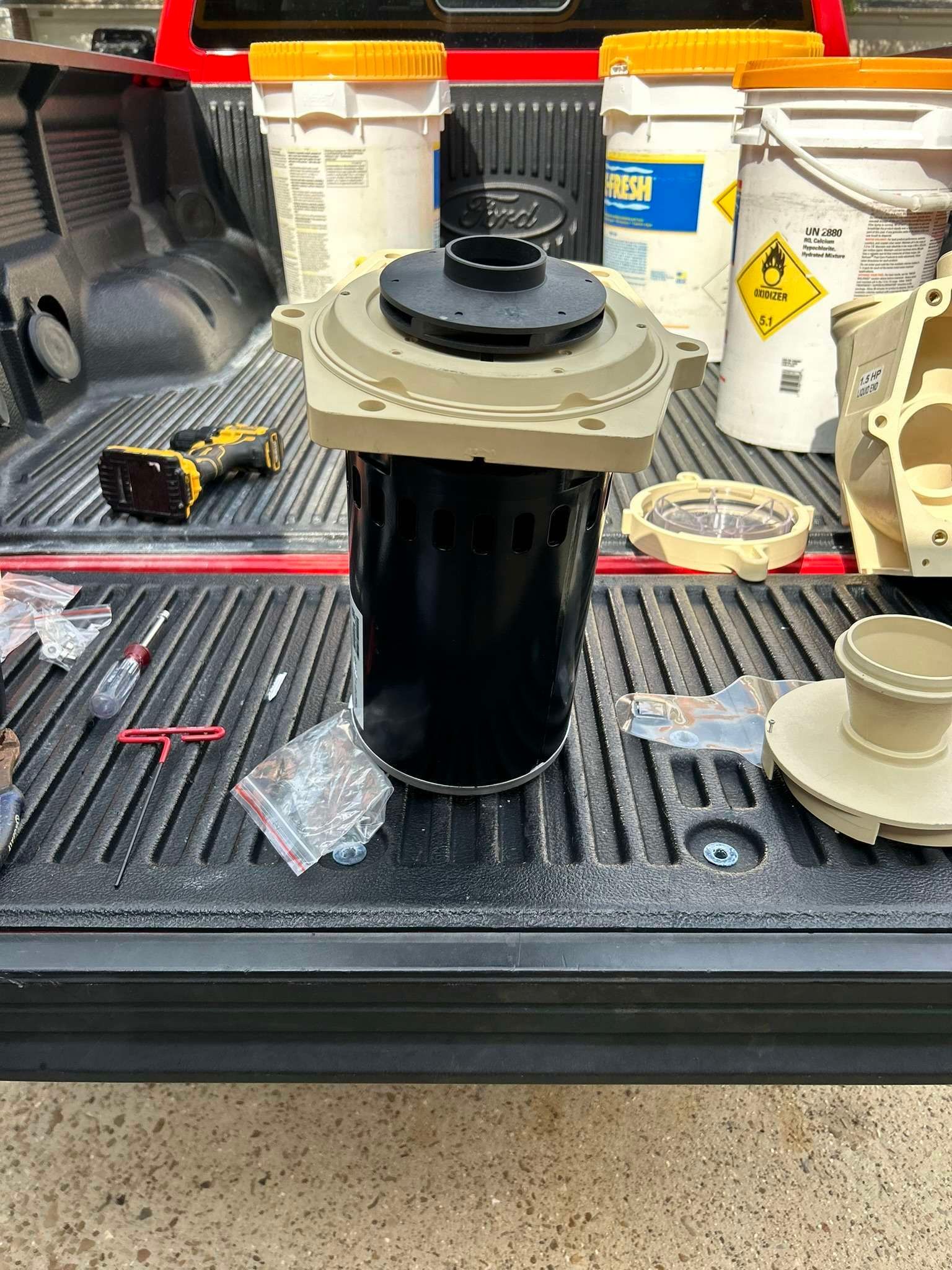 A black filter with tan top sits in a truck bed, surrounded by tools and cleaning chemicals.