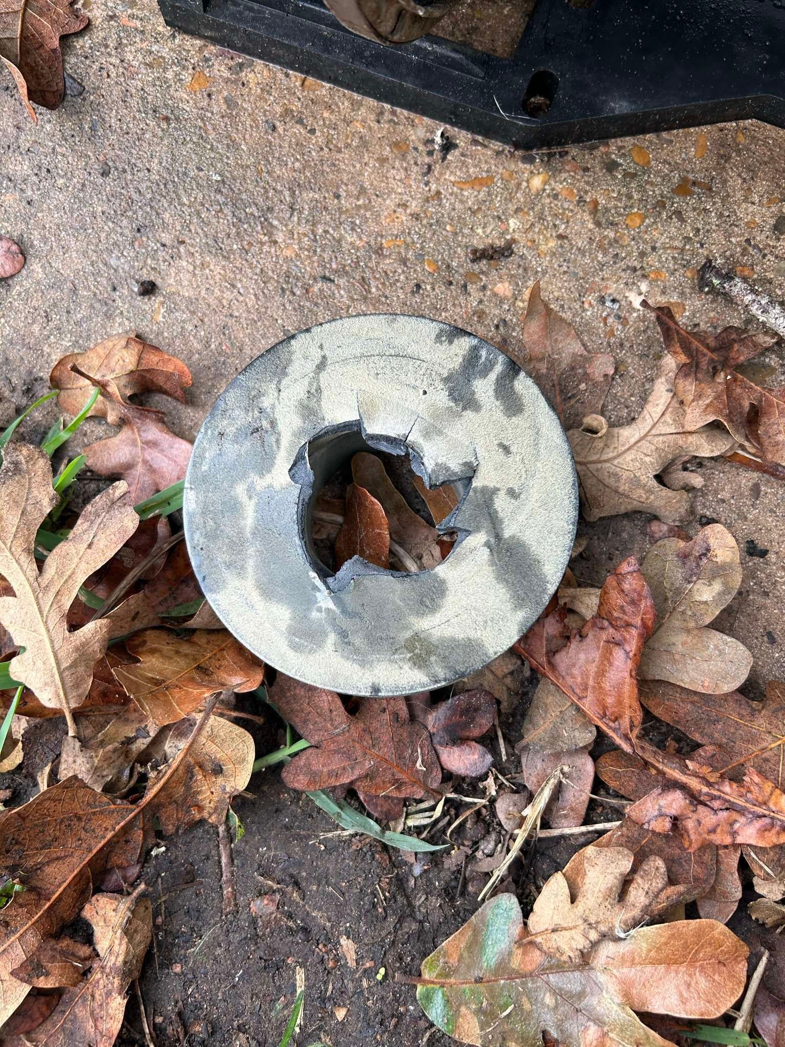 Concrete disc with hole, resting on leaves.