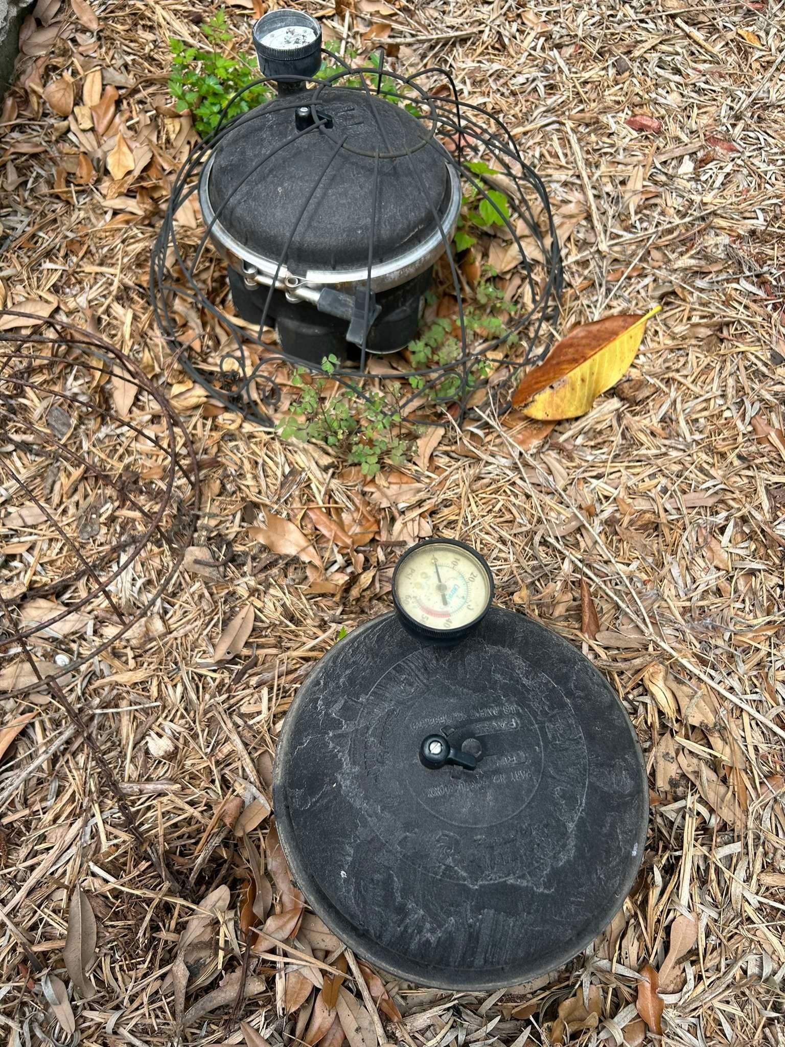 Two black irrigation system control boxes with gauges in mulch.