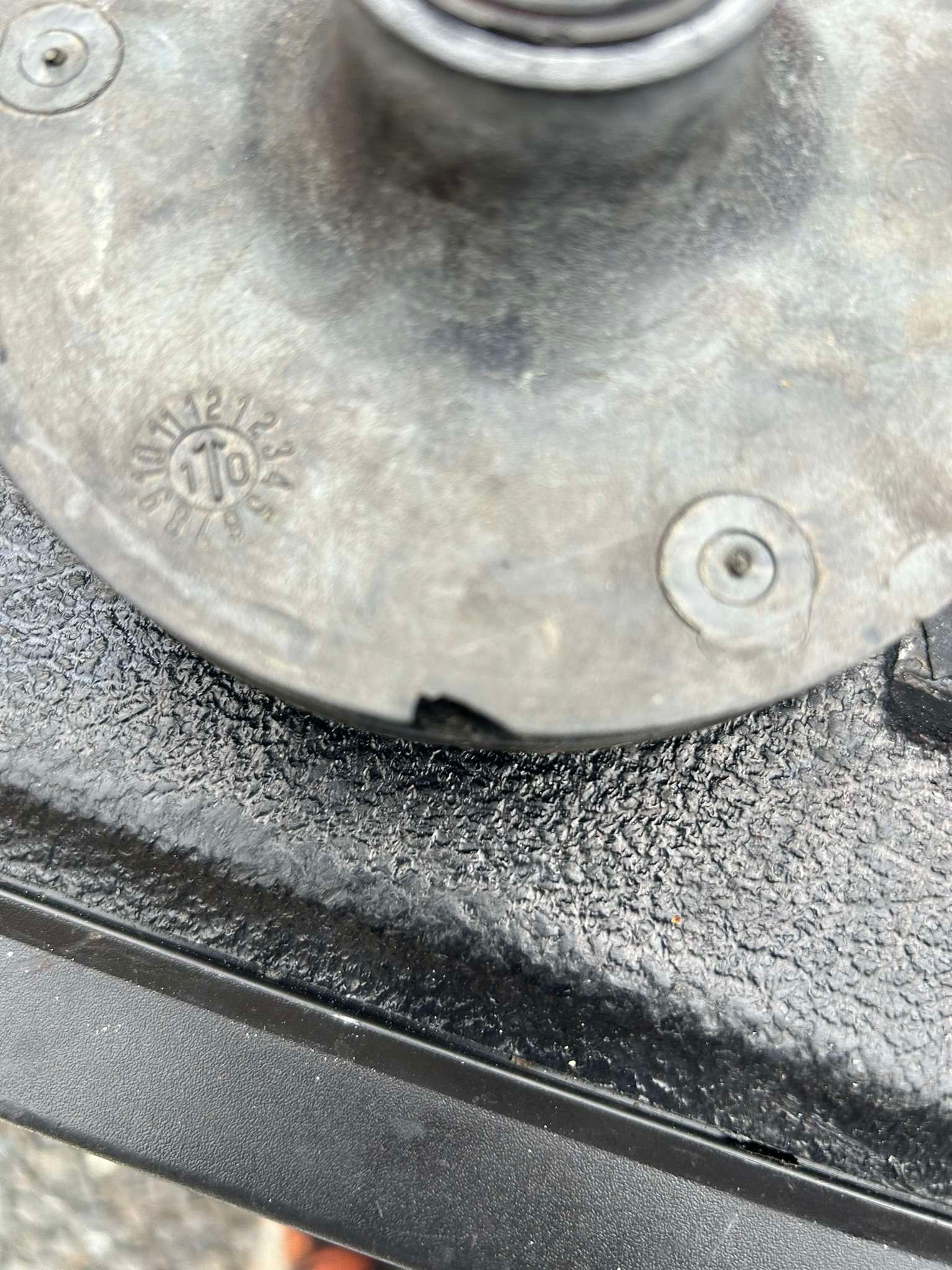 Close-up of a circular, grey metal part with the number 170 stamped on it, possibly an automotive component.