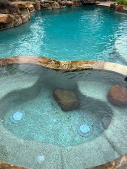 A spa and pool with clear, blue water surrounded by natural rock formations.