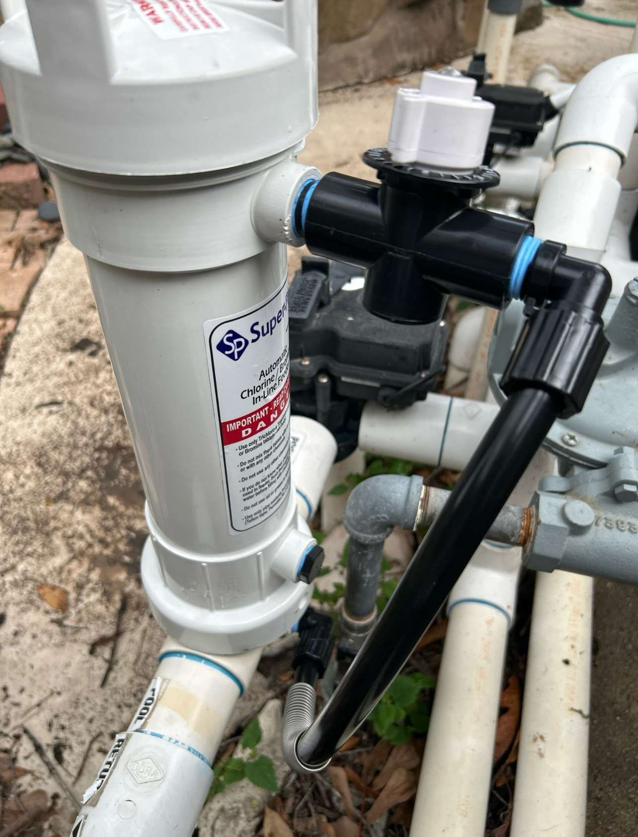White pool filter connected to black pipes and valves.