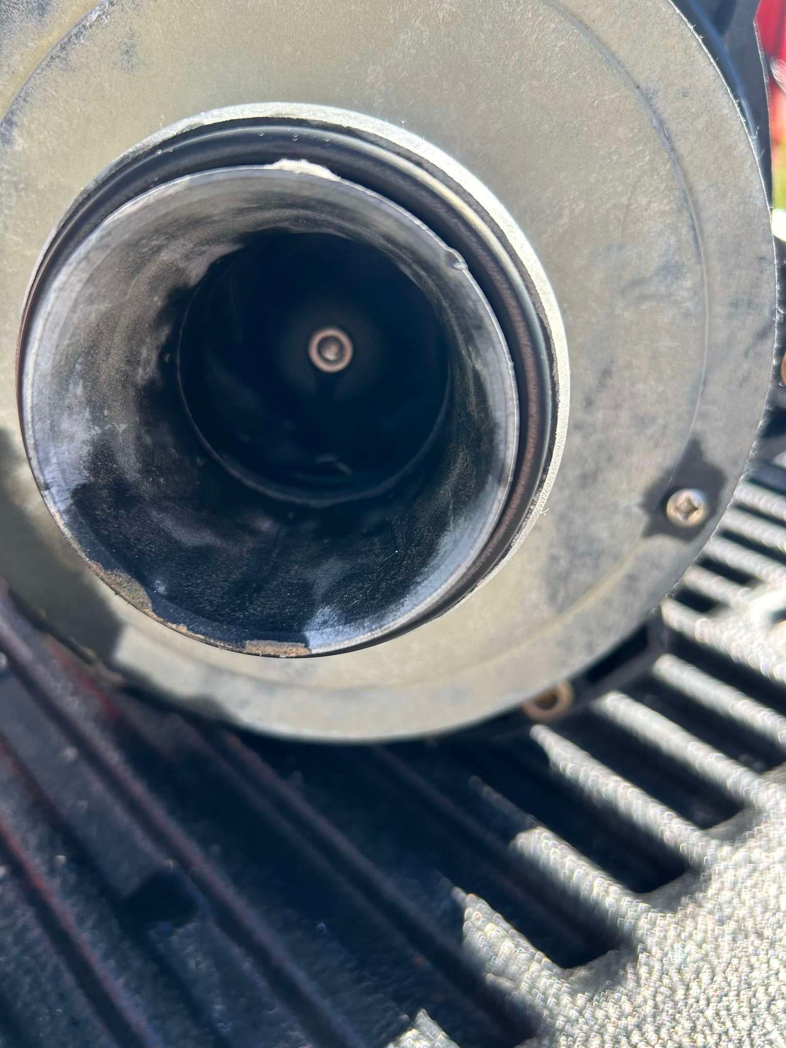 Close-up of a dark cylindrical object's interior with a small metal pin. White residue lines the rim.
