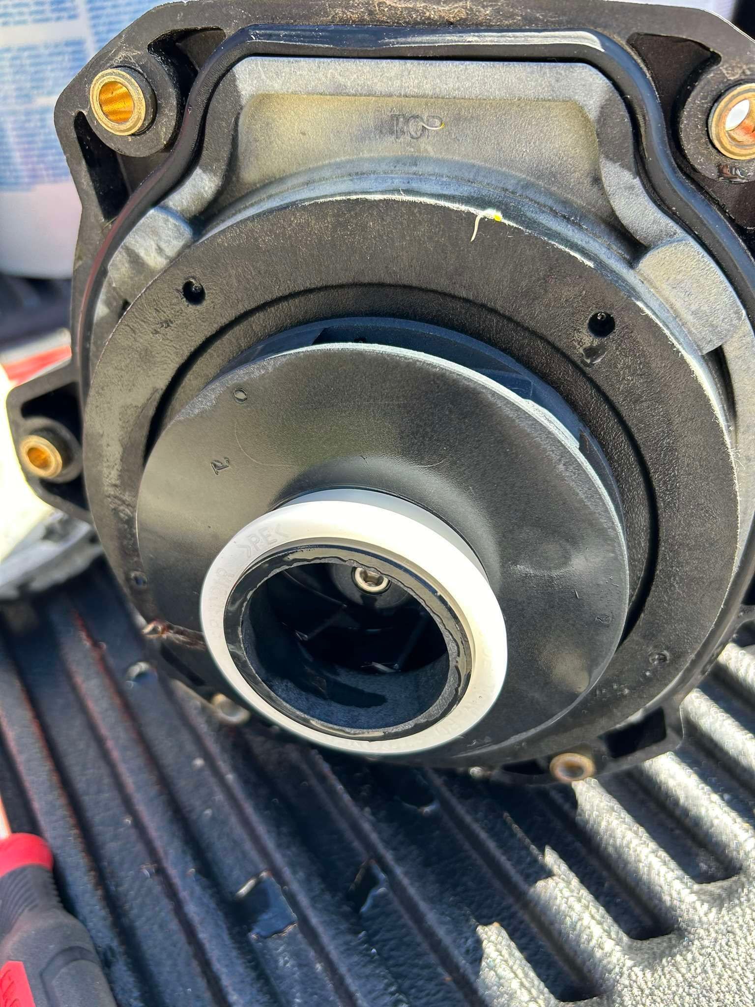Black and gray spa pump disassembled, showing the impeller and housing, outdoors on a truck bed.