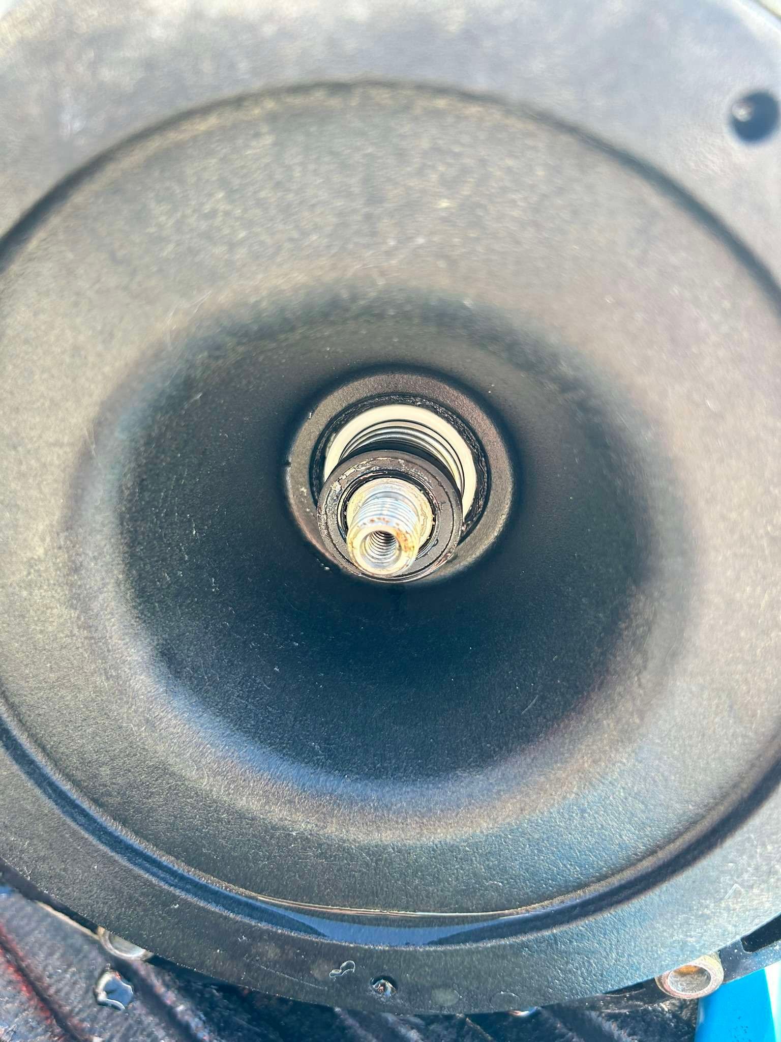 Black pump component interior, showing a central shaft with corrosion.