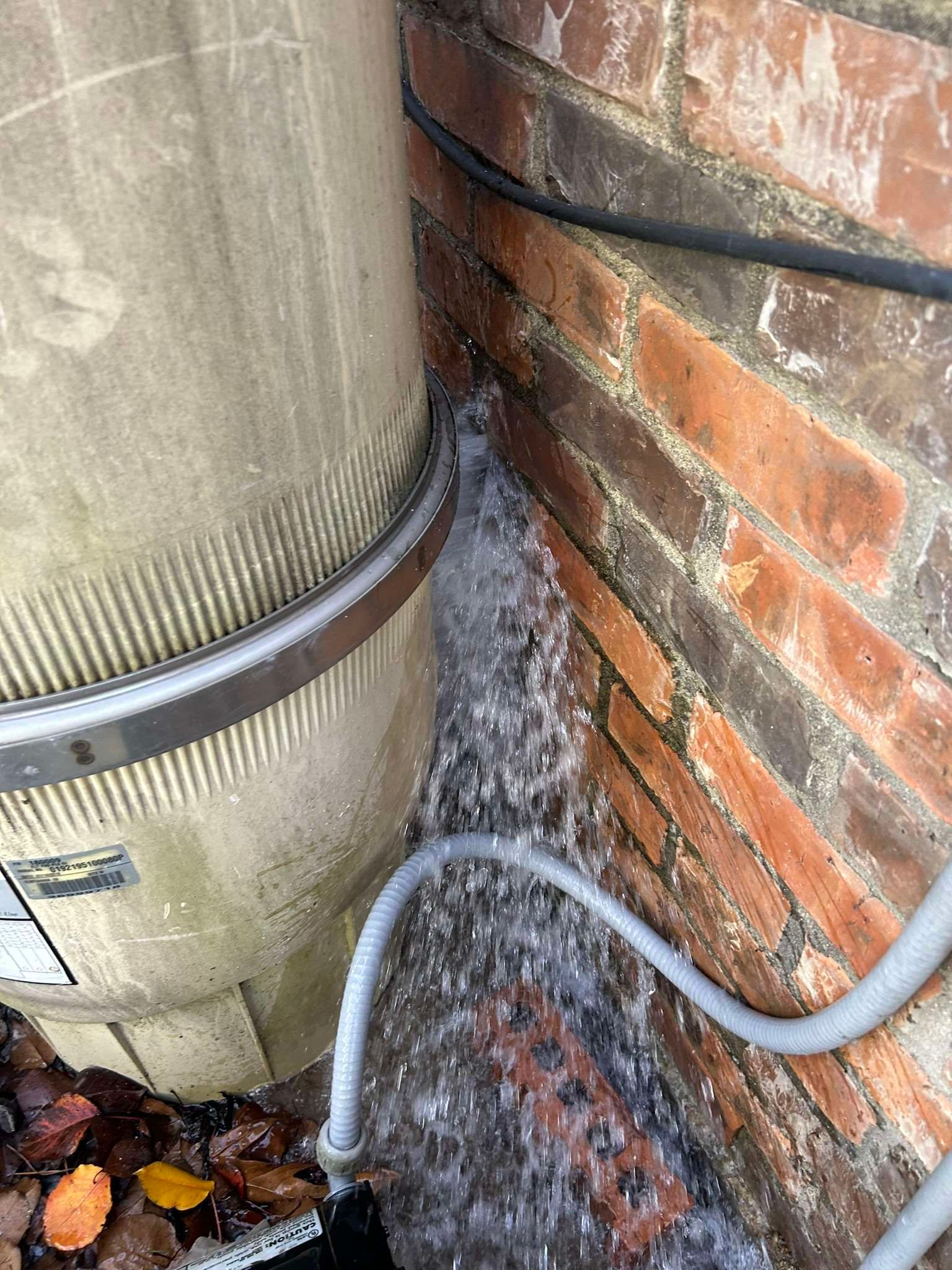Water gushing from a pool filter near a brick wall. A filter band secures the tank.