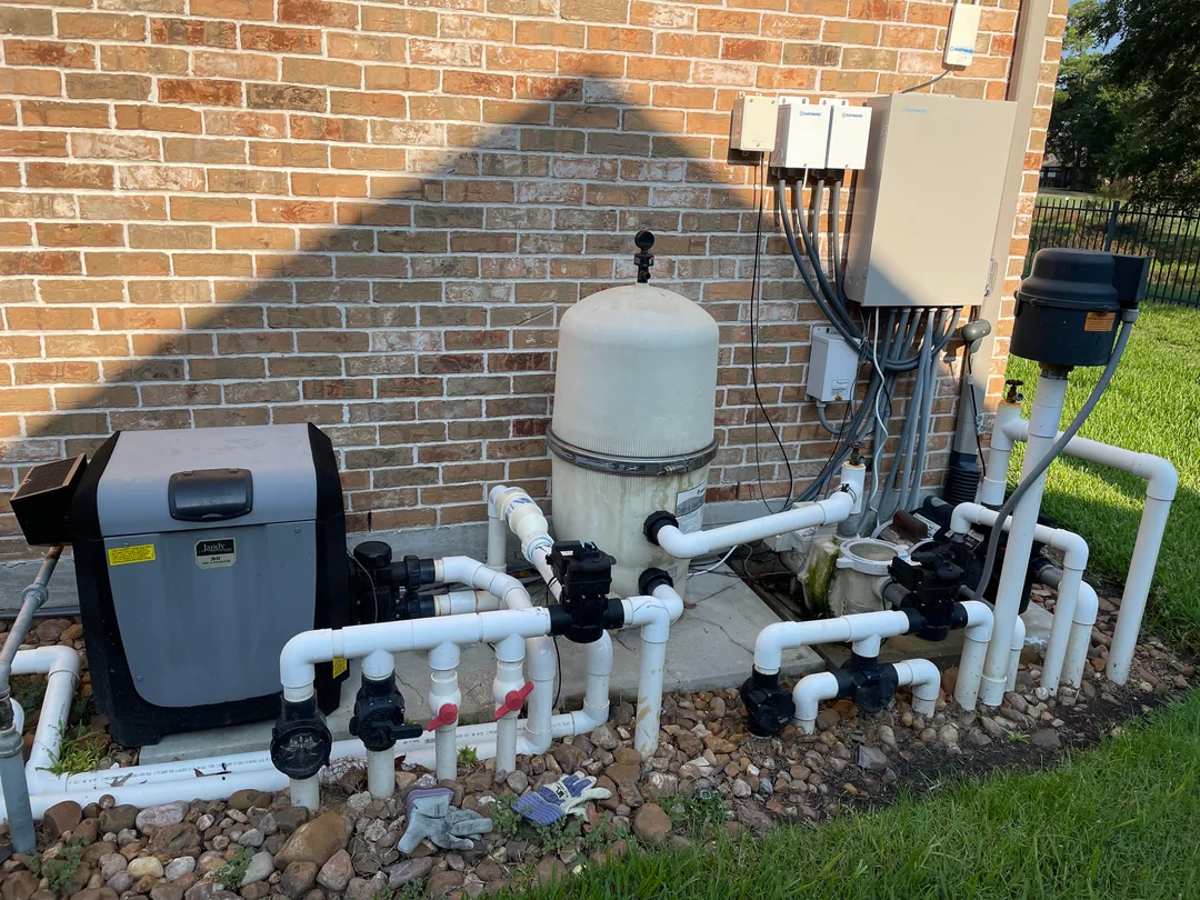 Pool technician in red shirt and hat, working on equipment. Tools and open toolbox visible.