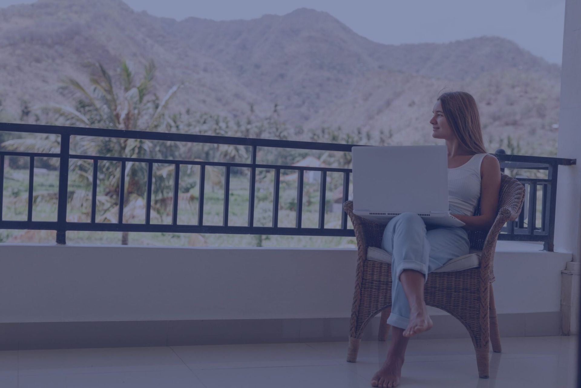 a woman is sitting on a balcony using a laptop computer .