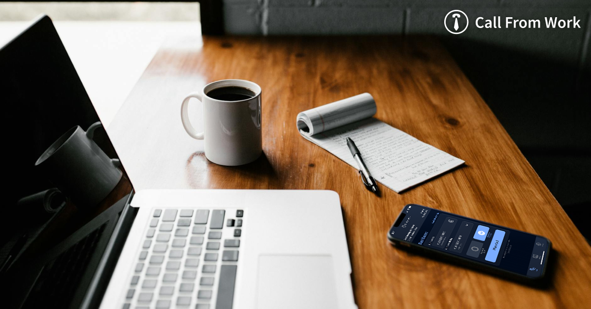 A desk with a laptop a cup of coffee a notebook and a cell phone