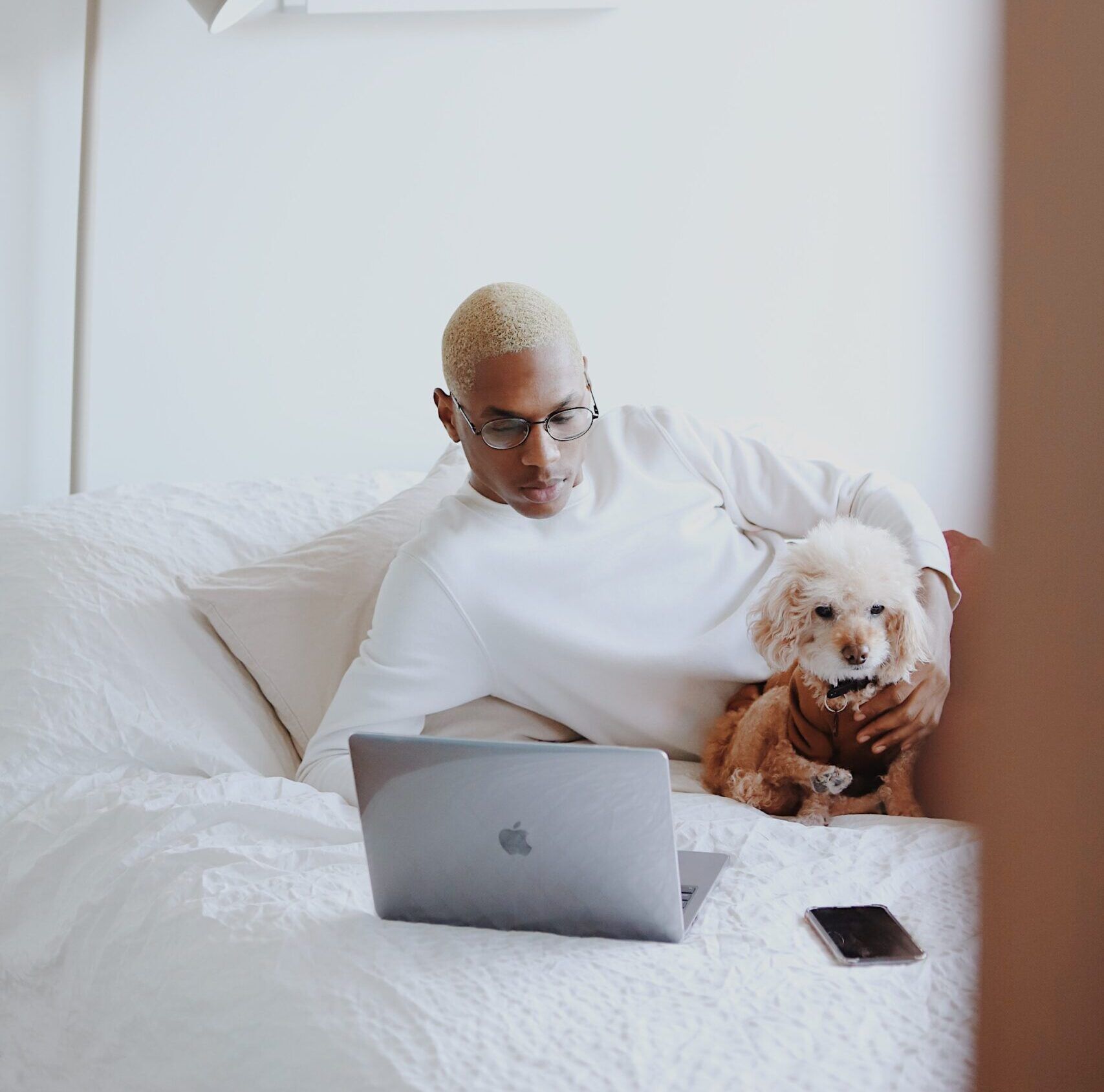 a man is laying on a bed with a dog and a laptop
