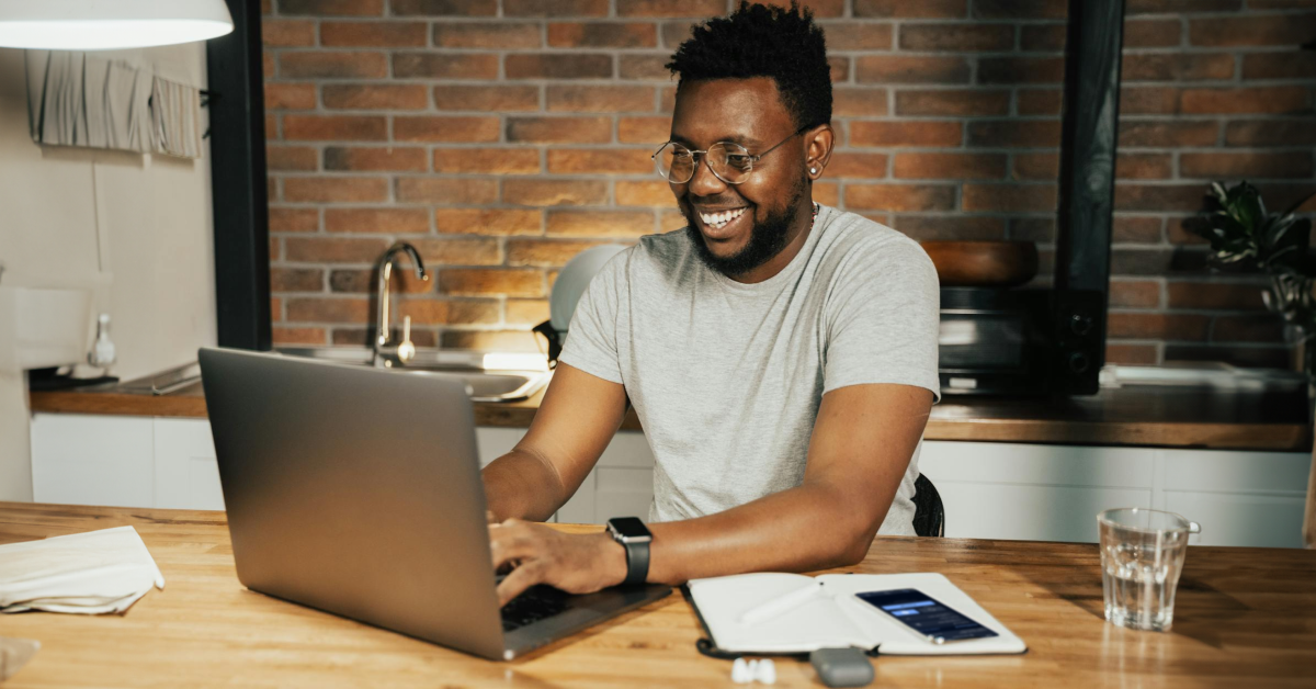 A man is sitting at a table using a laptop computer.