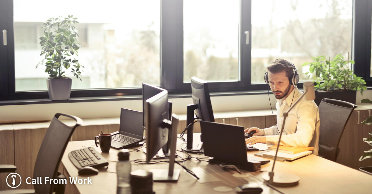 A man wearing headphones is sitting at a desk in front of a computer.