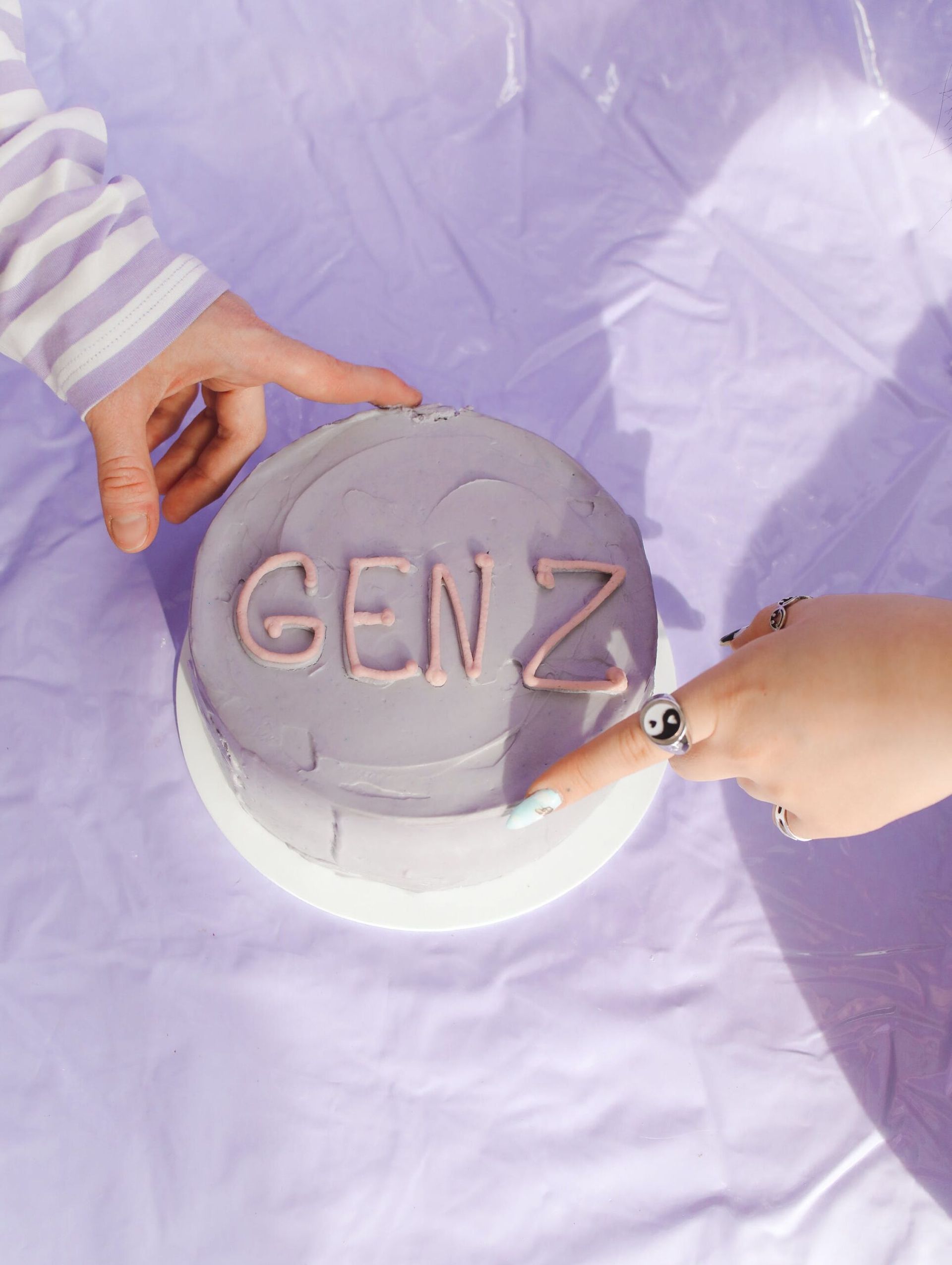 a person is holding a purple cake with the word genz on it .