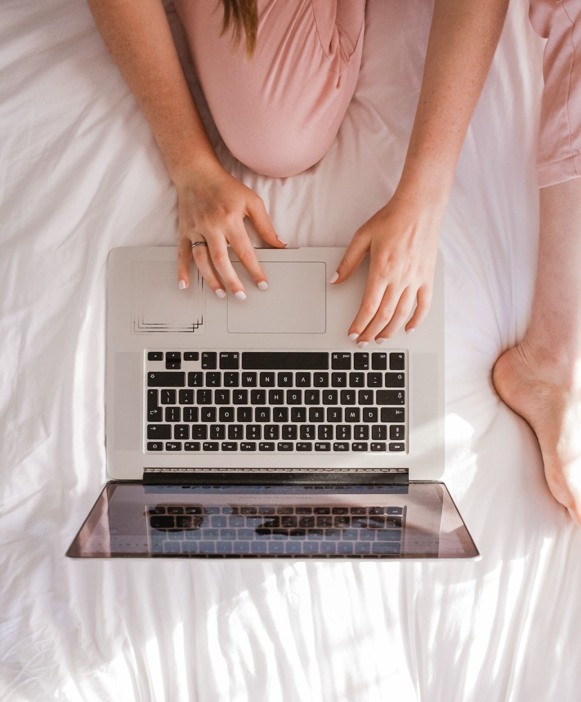 a woman is sitting on a bed using a laptop computer