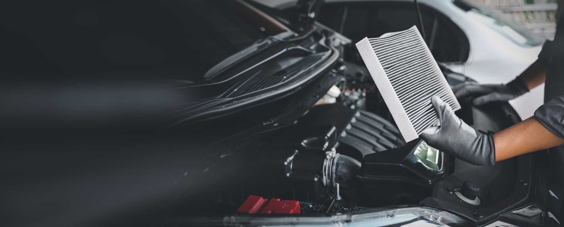 A person is holding a filter in front of a car.
