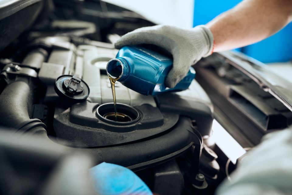 A person is pouring oil into a car engine.