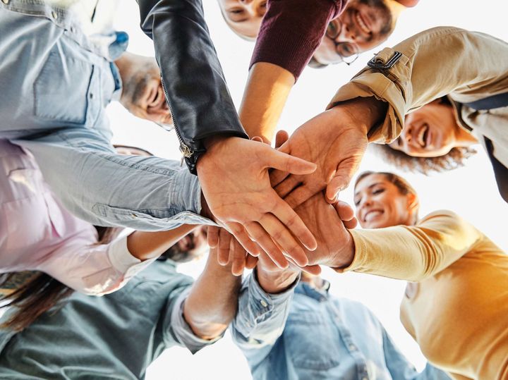 a group of people are putting their hands together in a circle