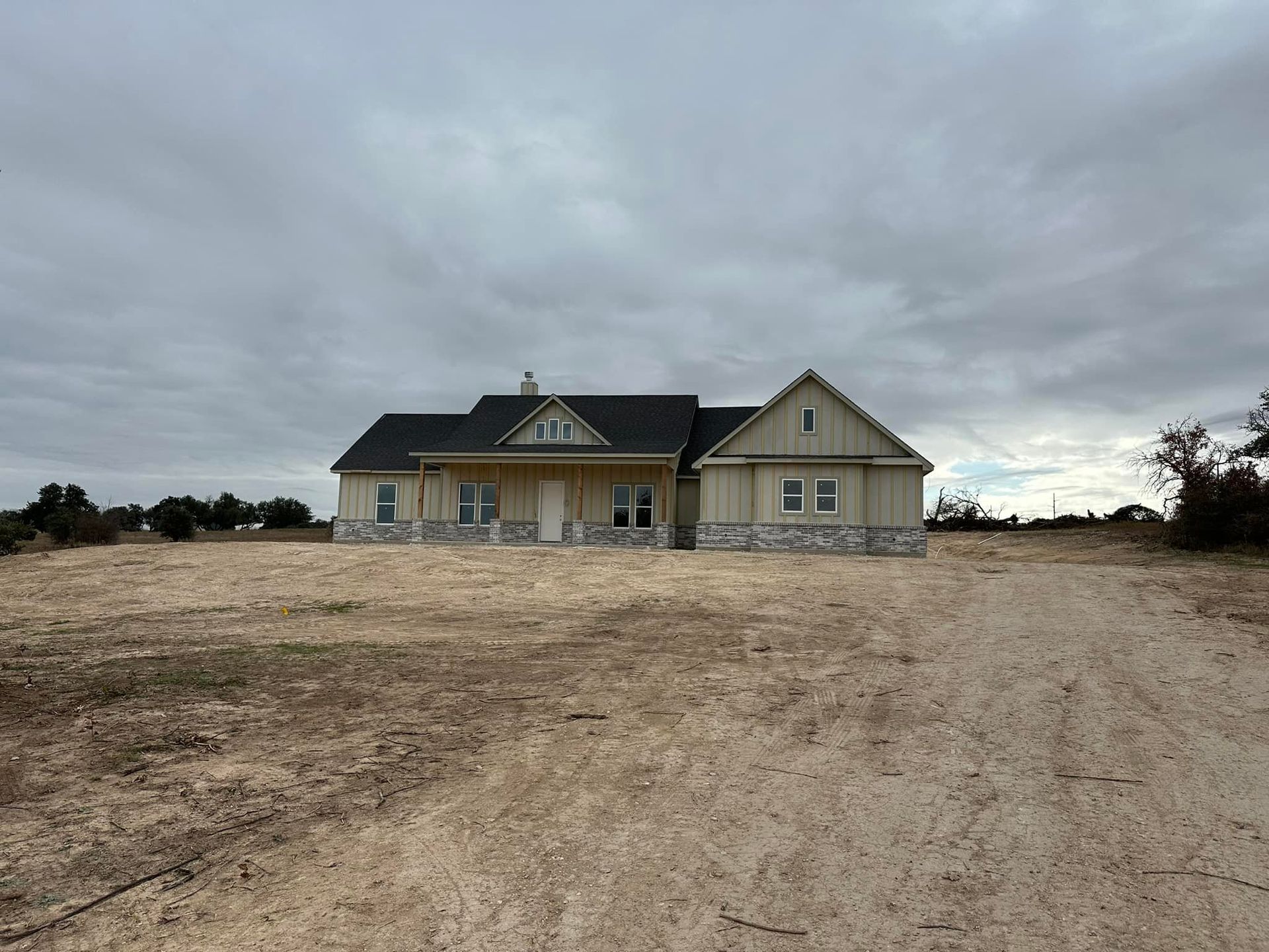 A house is sitting in the middle of a dirt field.