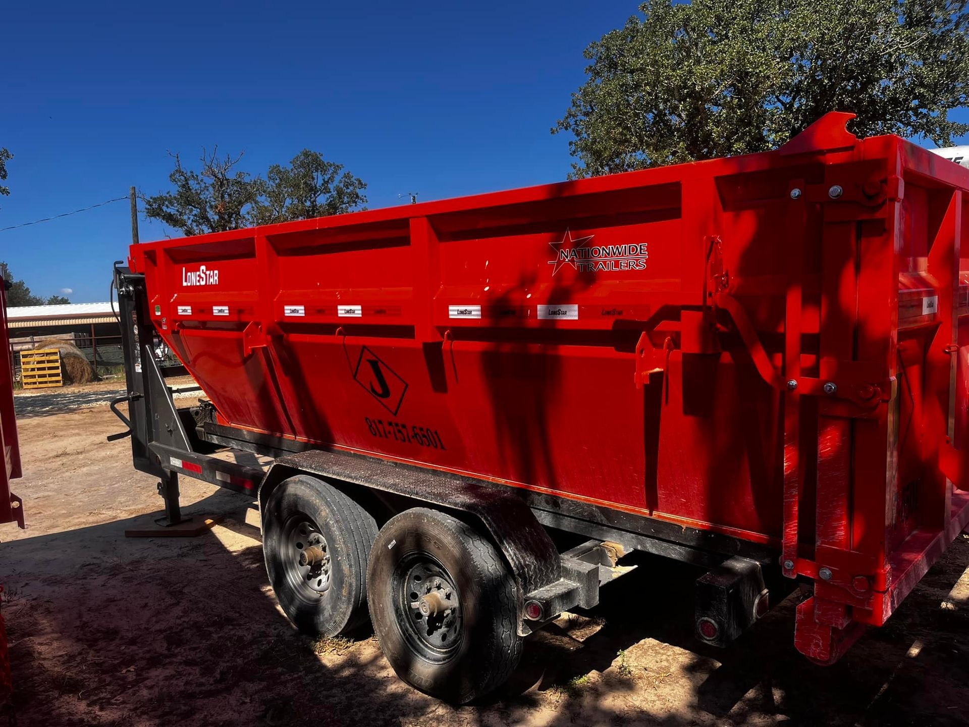 A red dump truck is parked in a dirt lot.