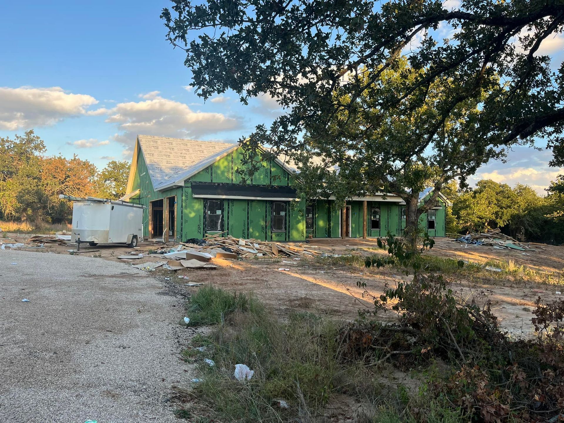 A house is being built on a dirt road next to a tree.