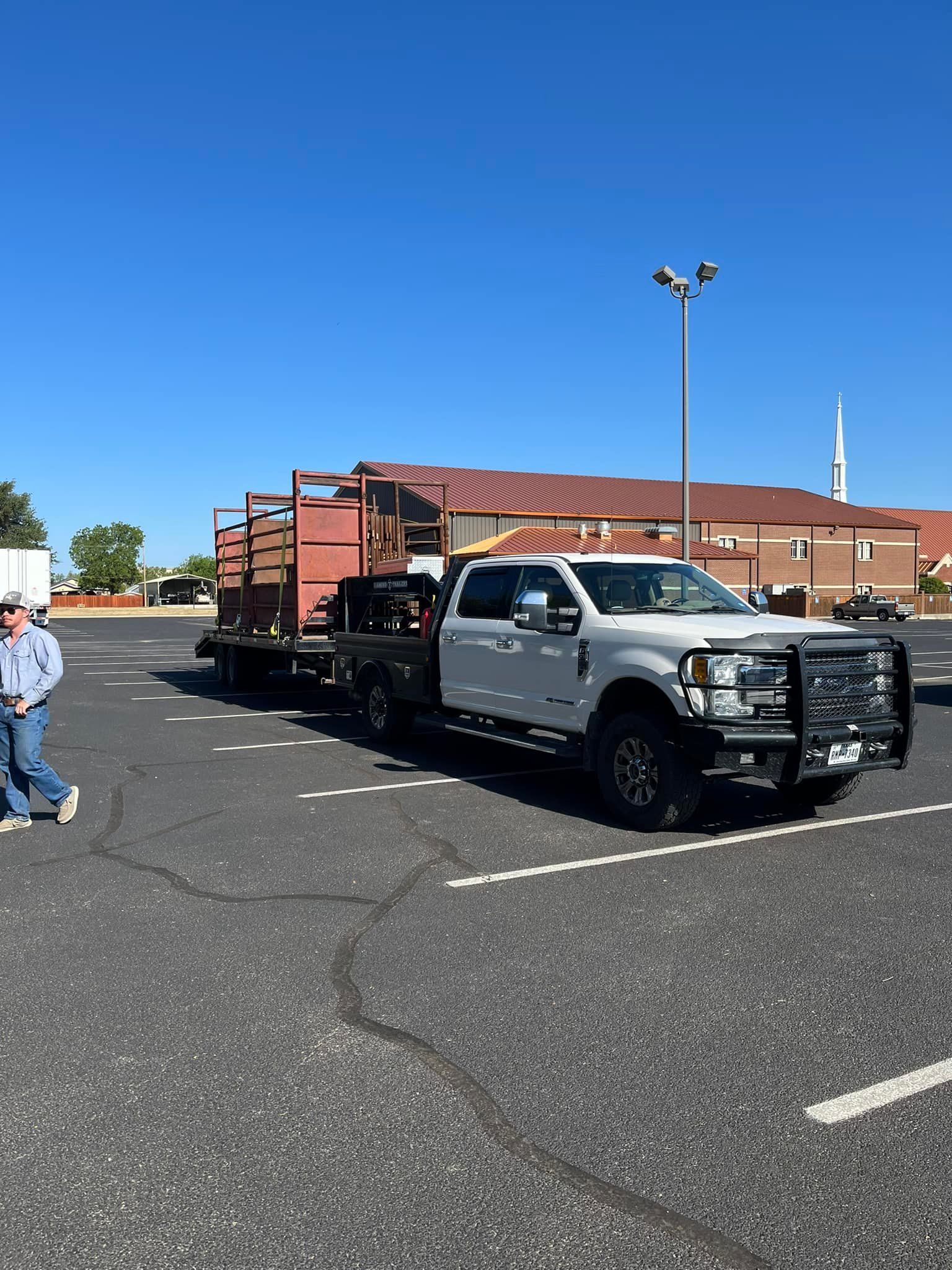 A white truck with a trailer attached to it is parked in a parking lot.