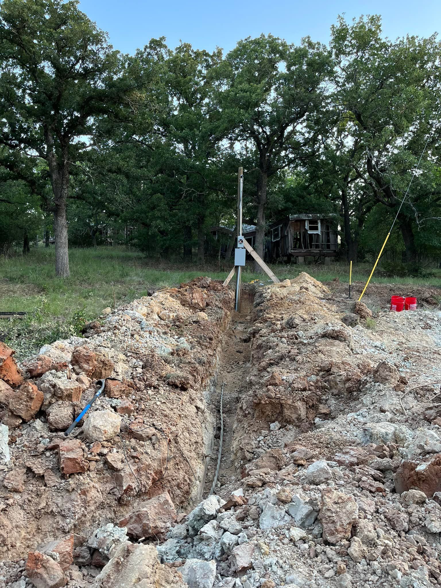A pile of dirt and rocks in a field with trees in the background.