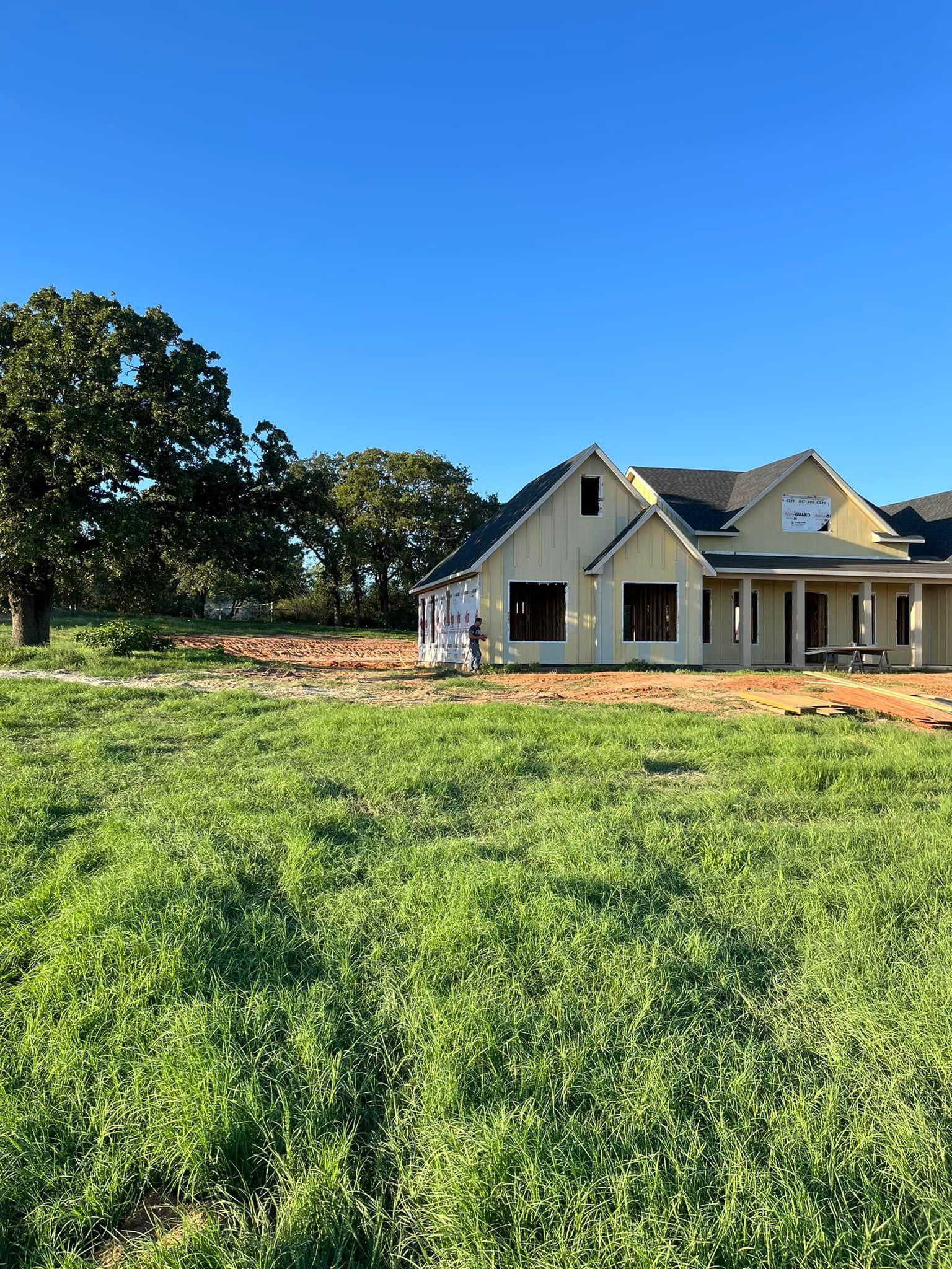 A house is being built in the middle of a grassy field.