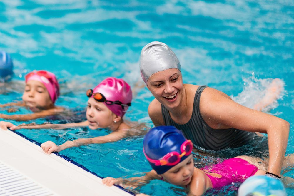 A woman is teaching a group of children how to swim in a swimming pool.