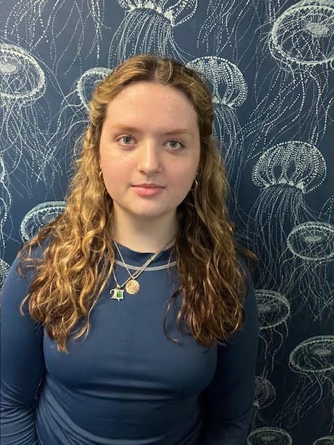 A young woman is standing in front of a wall with jellyfish on it.