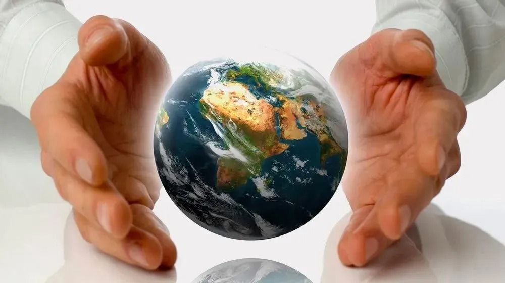 Dos manos ahuecadas alrededor de un globo terráqueo brillante sobre un fondo blanco liso.