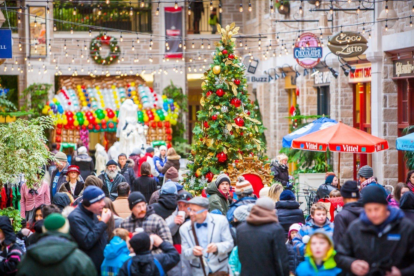Christmas at Old Quebec Street Mall - adults and children are buzzing around different vendor shops that are decorated with Christmas Trees, wreathes, and lights.