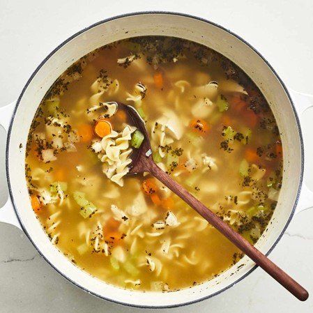 A bowl of chicken noodle soup with a spoon.