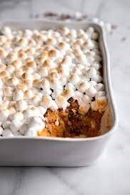 A white baking dish with a sweet potato casserole topped with mini marshmallows in it.