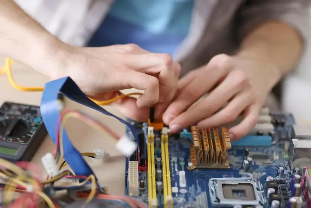 A man is working on a computer motherboard with a screwdriver.