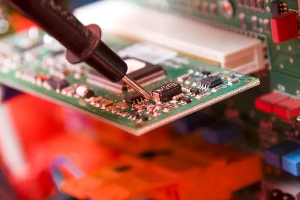 A close up of a person using a multimeter on a motherboard.
