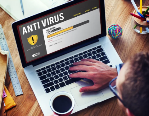 A man is using a laptop computer to scan for a virus.