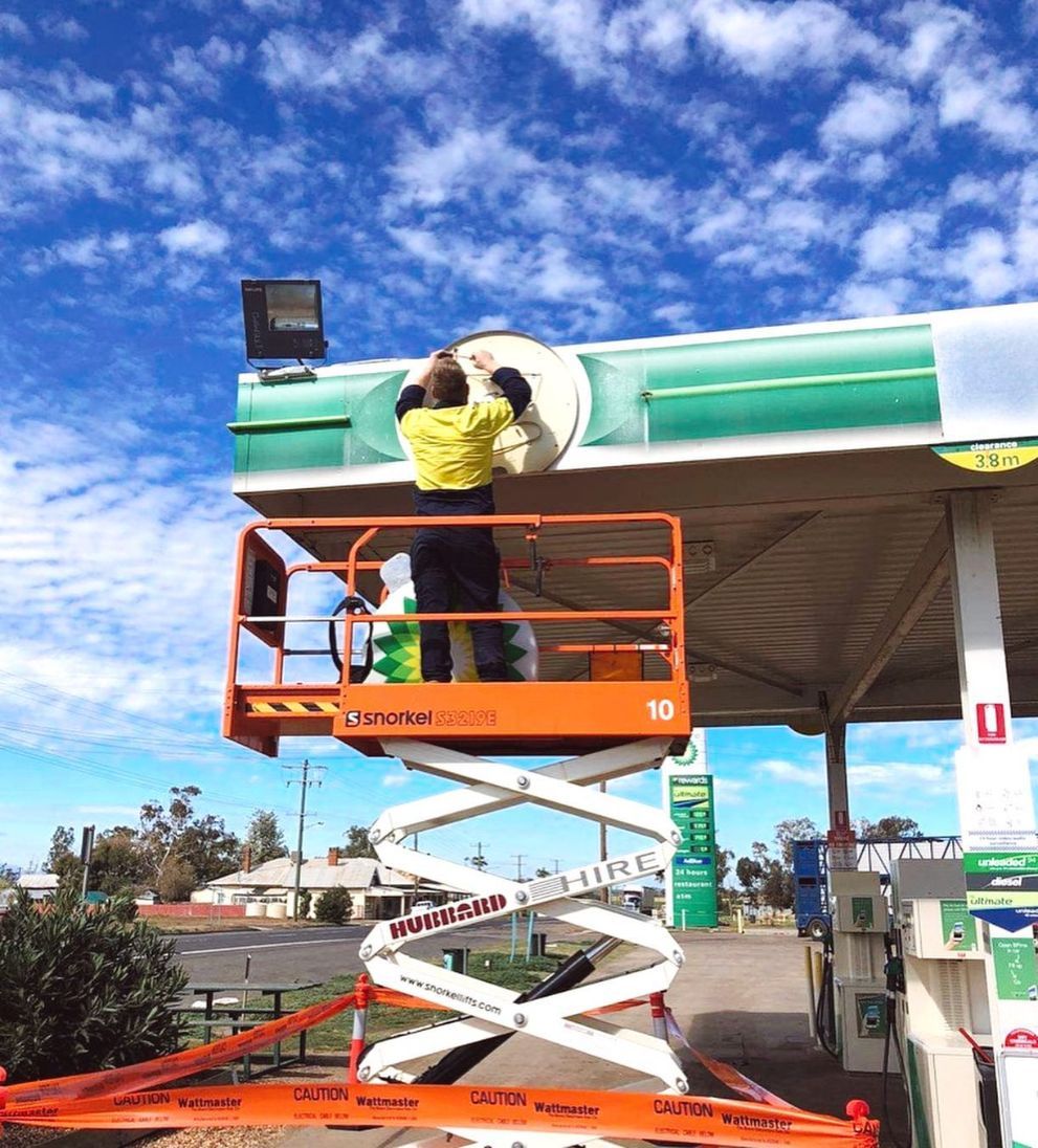 Electrician Fixing The Service Station Signage — Electrical Contractors in Tamworth, NSW