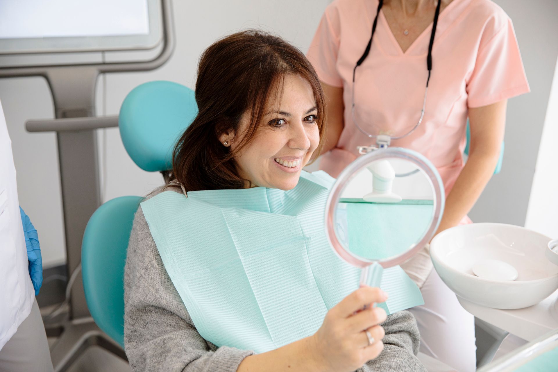 Dentist pointing at dental x-ray while explaining it to a patient in a bright dental office.